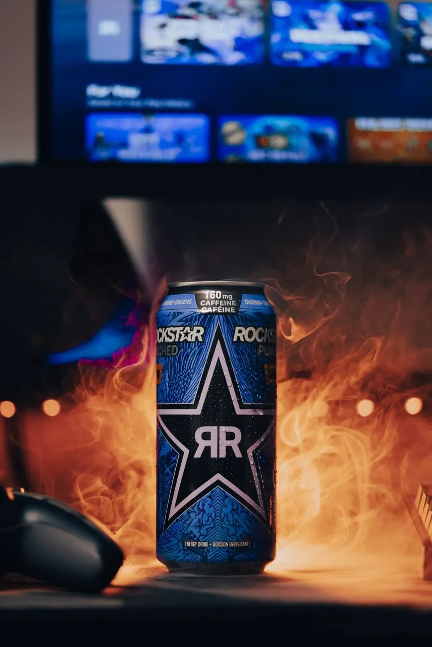 Can of Rockstar energy drink on a gaming desk, surrounded by smoke