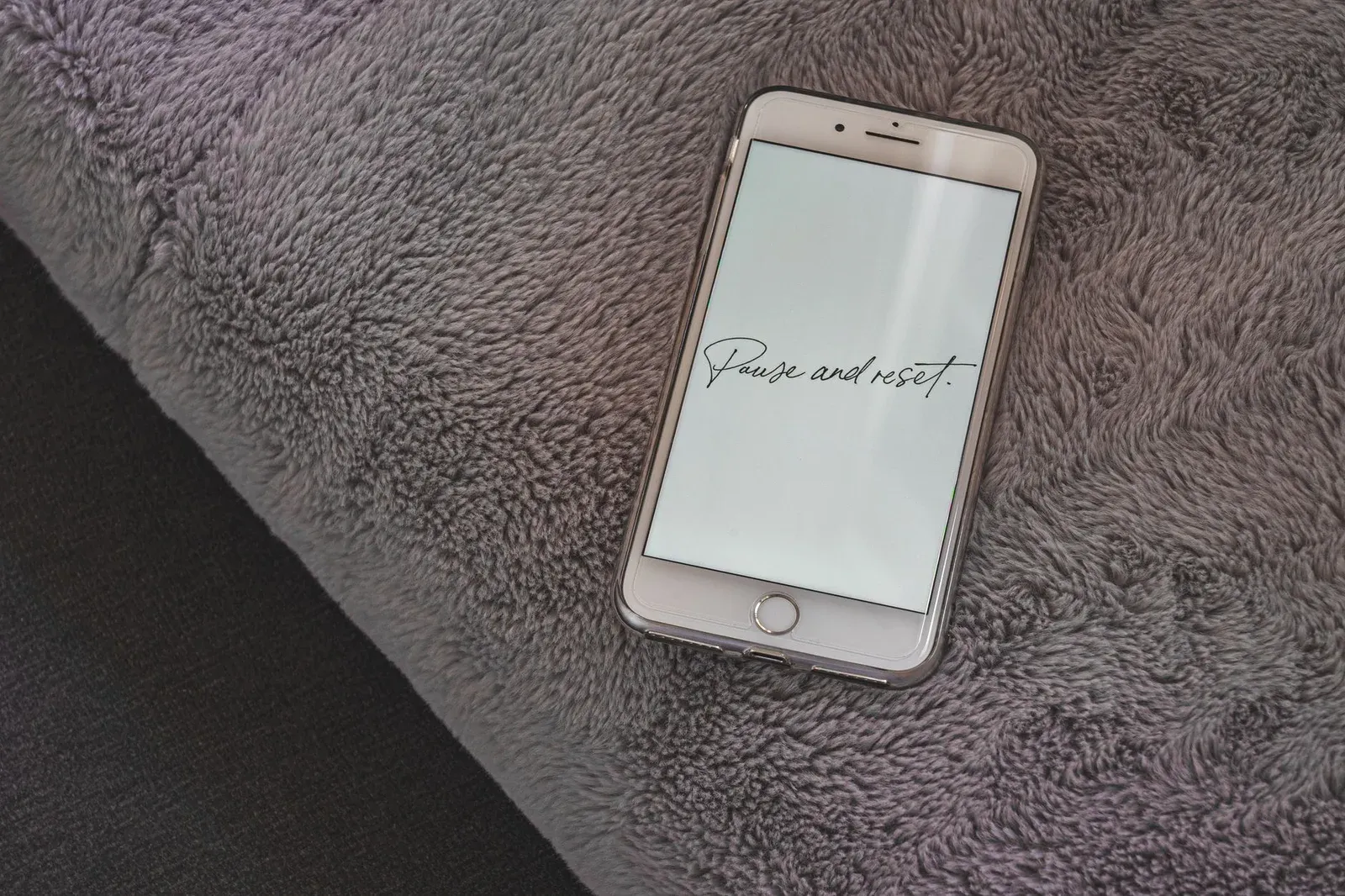 Smartphone on a gray blanket with "Pause and reset." written on the screen
