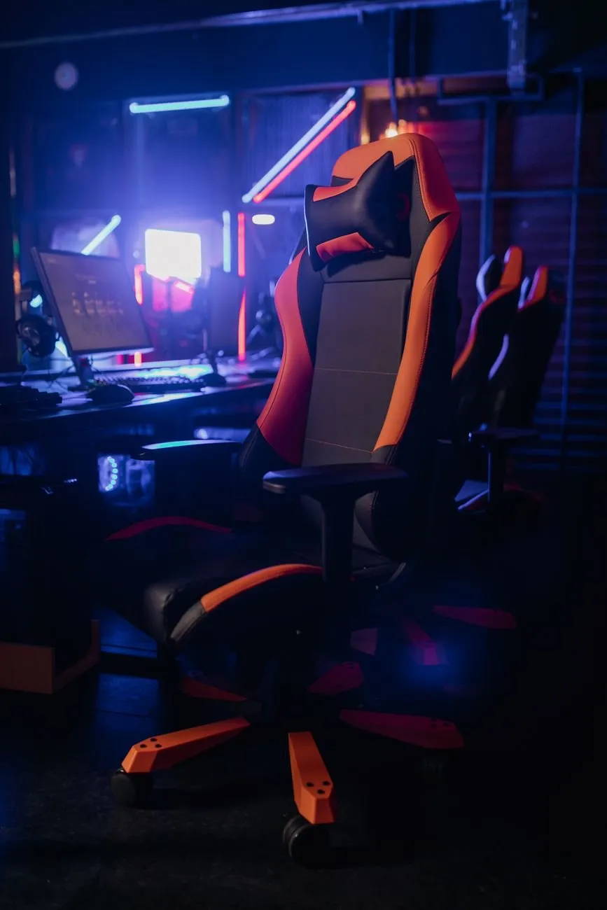 Black and orange gaming chair in front of a desk lit by neon lights
